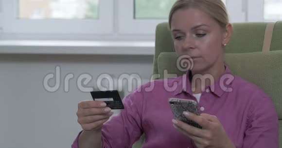 网上购物时微笑的女人手里拿着信用卡的画像视频的预览图