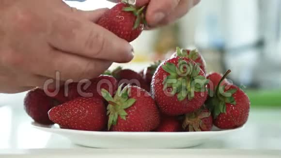 厨房里的男人选择和清洗盘子上的草莓水果视频的预览图