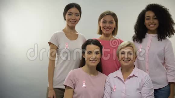 穿着粉红色衬衫戴着乳癌丝带的女人竖起大拇指对着镜头视频的预览图