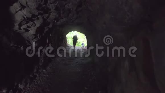 带着手电筒的背包的女游客走进了一个黑暗的洞穴视频的预览图