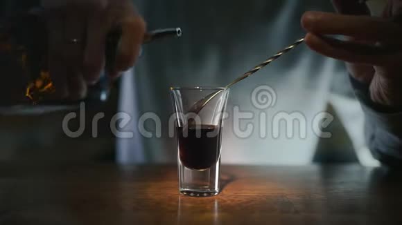 酒保将透明的酒精倒入分层的镜头中用酒吧勺子缓慢地用酒精勺将酒精倒进去视频的预览图