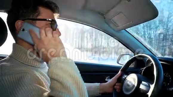冬天一个人在城市之间的公路上开车他拿着智能手机开始说话放下手机视频的预览图
