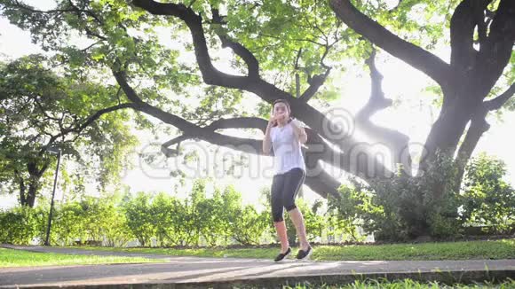 亚洲女子拳击在绿色公园用大树和阳光取暖视频的预览图