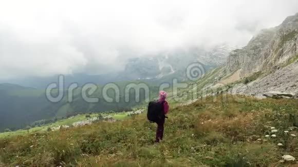 年轻女子背着背包走向山顶慢动作女士正在美丽的高加索山脉徒步旅行视频的预览图