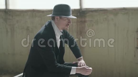一个戴着帽子的英俊自信的人把硬币扔到一座废弃的建筑物里黑手党头目视频的预览图