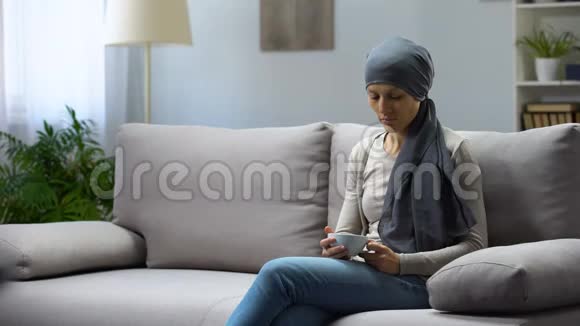 患有癌症的疲惫的年轻女子坐在家里喝茶病情得到缓解视频的预览图