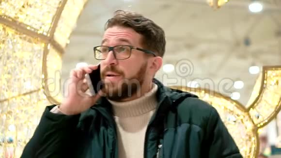 戴眼镜的胡子男在智能手机上说话视频的预览图