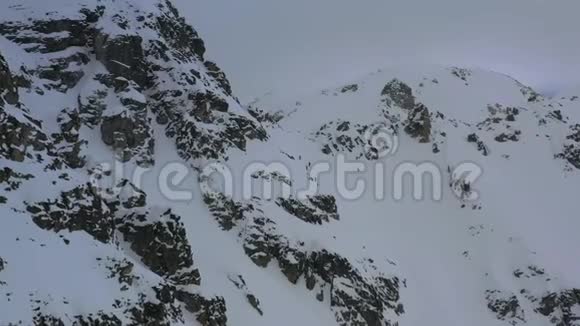 暴风雪期间人们骑着滑雪板上山空中拍摄4k的画面视频的预览图