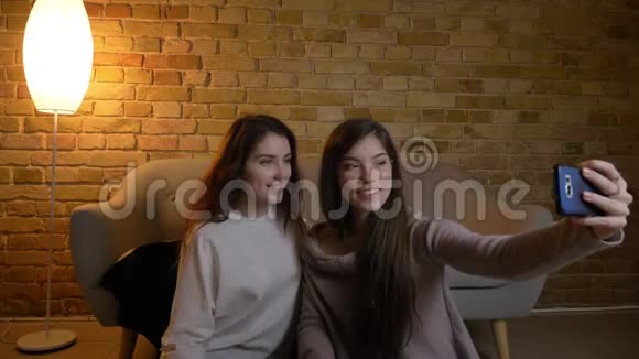 年轻白种人女孩坐在地板上在舒适的家里用智能手机制作漂亮的自拍照片的肖像视频的预览图