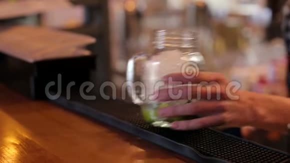酒保把冰放在一个大玻璃杯里在酒吧特写中煮莫吉托视频的预览图