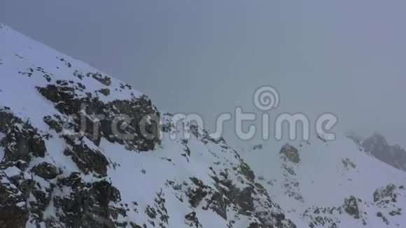 暴风雪期间覆盖着雪的黑暗和雾蒙蒙的山峰空中拍摄的画面是4k视频的预览图