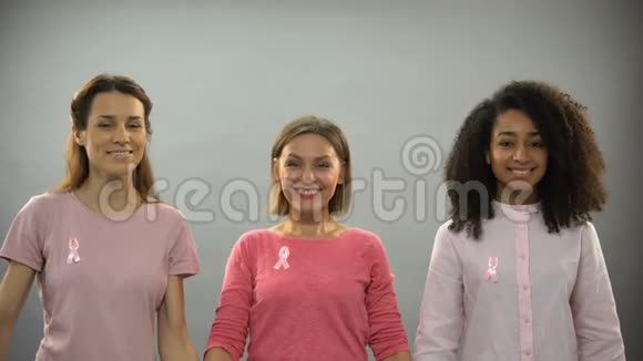 微笑的女人用粉红色的丝带举起双手对抗乳腺癌视频的预览图
