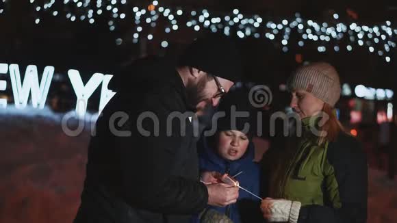 家人庆祝新年父亲点亮孟加拉灯在街上的夜晚冬天视频的预览图