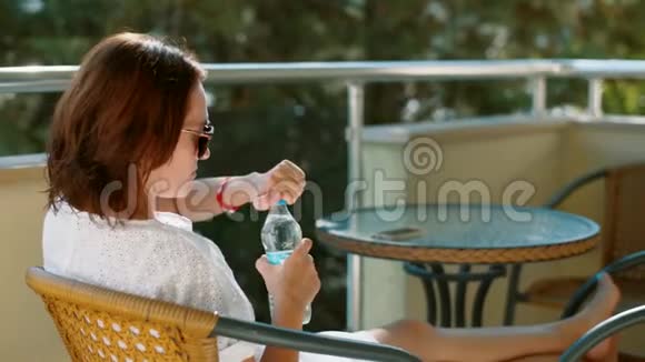 阳台上的女人打开一瓶水视频的预览图