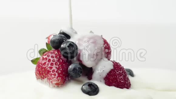 新鲜健康食品草莓和蓝莓倒入酸奶酸奶和鲜奶油中的浆果视频的预览图