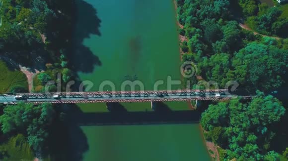 空中放大绿色河流上的桥梁上的交通视野4K视频的预览图