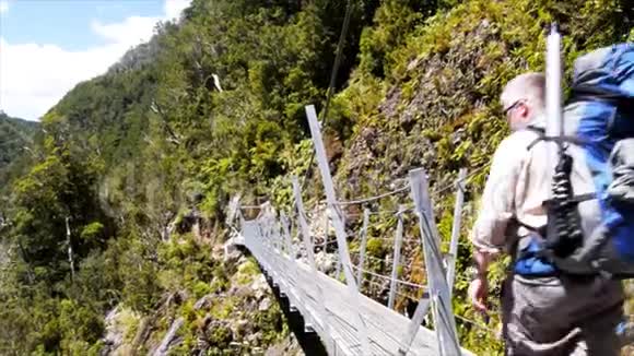 一个徒步旅行者穿过一座吊桥的平底锅视频的预览图
