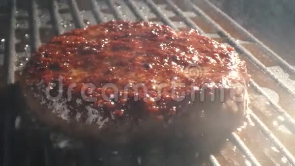 烟雾从烤架上的切块上方升起美味的牛肉汉堡在烤架上翻转视频的预览图