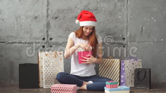 快乐的红发女孩打开一个盒子里面有礼物圣诞节的概念视频的预览图