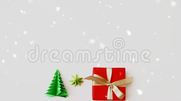 在礼品盒和圣诞树折纸上下雪视频的预览图