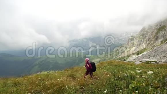 年轻女子背着背包走向山顶慢动作女士正在美丽的高加索山脉徒步旅行视频的预览图