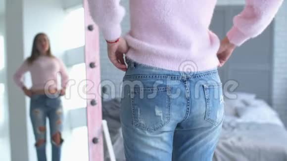 一位成功节食后展示旧牛仔裤的女士视频的预览图