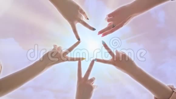 人们用他们的手指在粉红色的神奇天空的背景下形成恒星形状阳光照耀视频的预览图