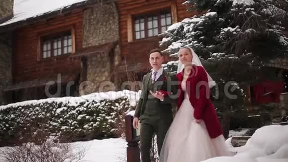 年轻的新婚夫妇走着微笑着说话着手牵着楼梯在滑雪胜地的村庄里有着木制的小屋视频的预览图