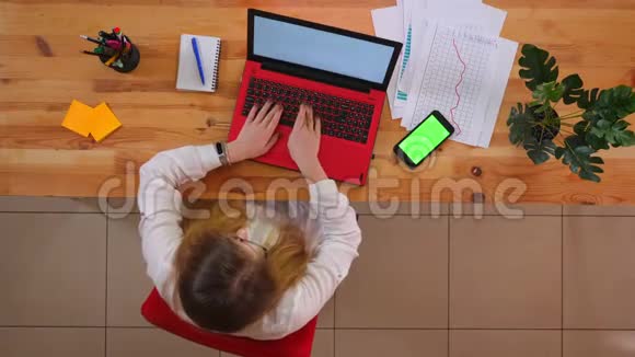 为年轻的白种人员工拍摄的特写镜头他们使用笔记本电脑桌上放着绿色屏幕的手机视频的预览图