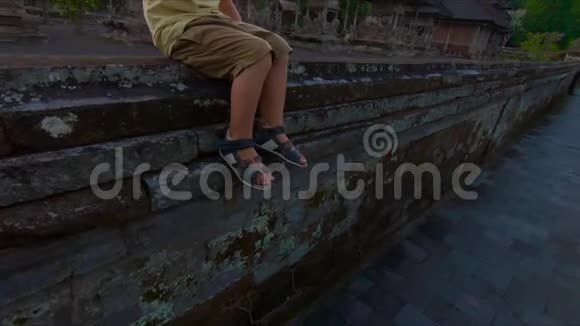 一个小男孩坐在塔曼阿云庙的墙上喝着塑料瓶里的水视频的预览图