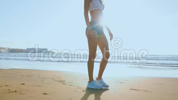 女孩穿着运动服腿站在海洋附近缓慢地抚摸着她的头发视频的预览图