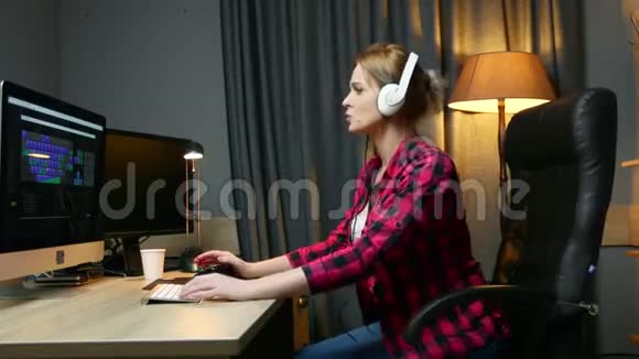 戴着耳机的年轻快乐女人坐在办公椅上听音乐跳舞下班后放松视频的预览图