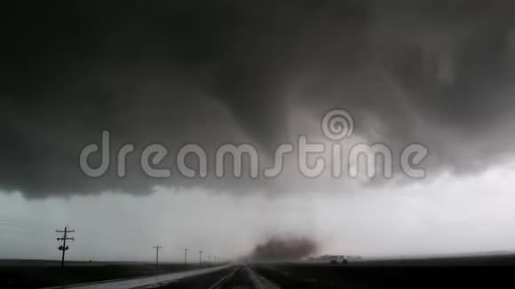 堪萨斯州一条高速公路上的一个大圆锥龙卷风和尘埃云的手持镜头视频的预览图