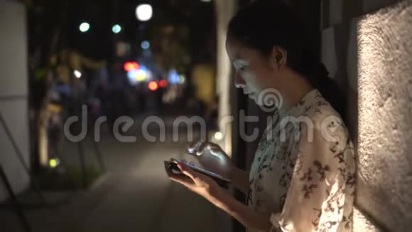 亚洲女人晚上在外面用智能手机上网视频的预览图