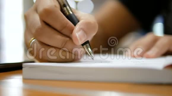 近距离拍摄女子手在纸笔记本上书写选择焦点浅景深视频的预览图