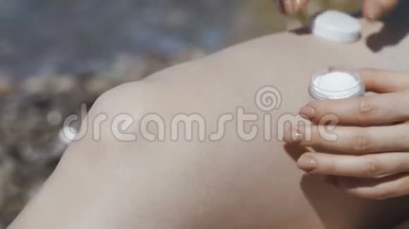 在热带海滩上为女性的双腿涂防晒霜视频的预览图
