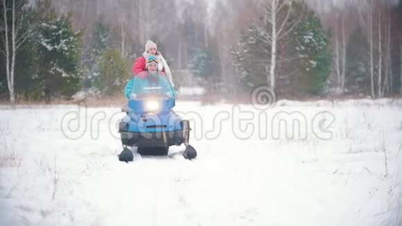 两个穿着五颜六色衣服的年轻漂亮女人在冬天的森林里骑着雪地摩托慢动作视频的预览图