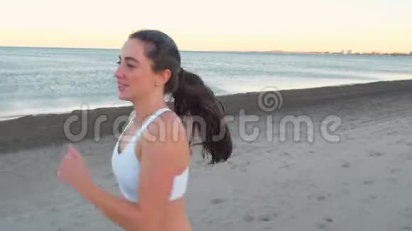 年轻女子正在做运动以恢复呼吸在沙滩上日出在秋天前面的景色命名视频的预览图