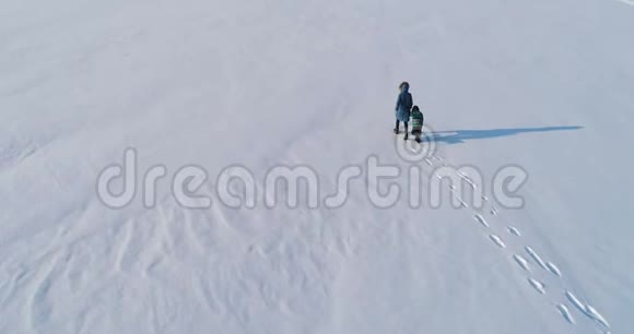 家庭时间一起散步和玩耍母亲和儿子在冬天携手穿过积雪覆盖的地区妈妈视频的预览图