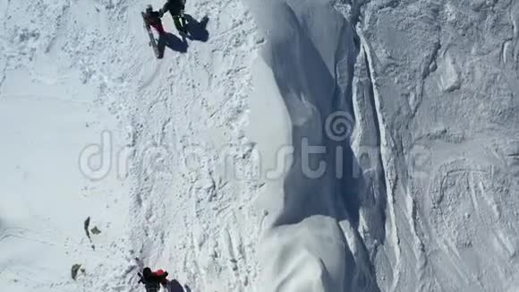一对夫妇手里拿着滑雪板在雪地上行走的俯视图视频的预览图