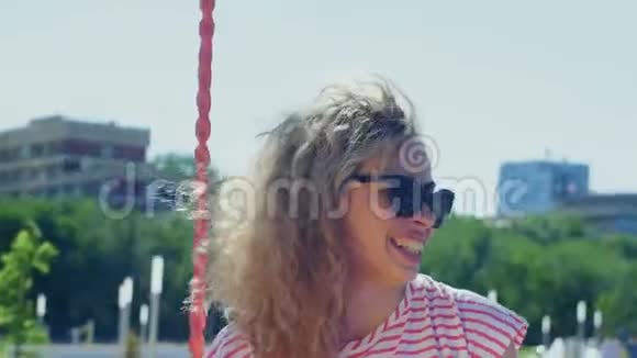 一个在夏天公园里荡秋千的卷发女孩视频的预览图
