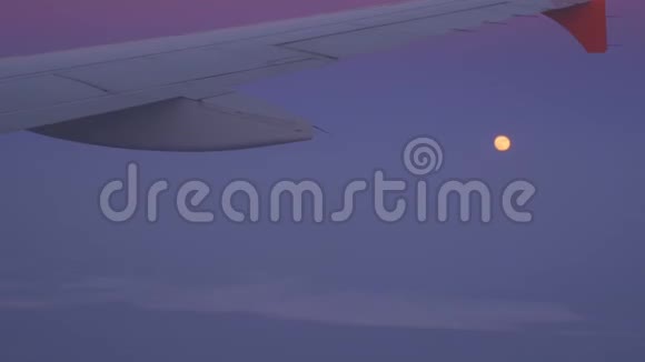 从飞机的窗户可以看到令人印象深刻的粉红色日落和明亮的大月亮视频的预览图