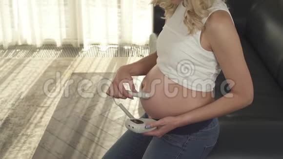 一个怀孕的金发女郎的侧视她正在检查胎儿的心跳她看着肚子微笑着视频的预览图