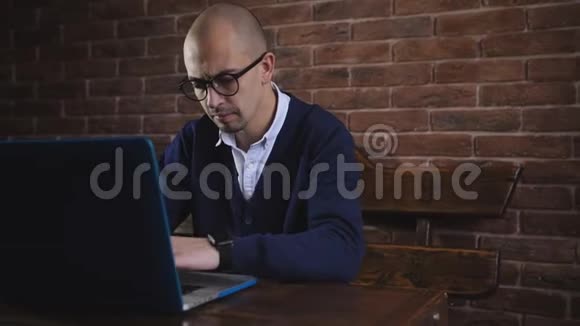 作者为笔记本电脑工作一个英俊的中年男子坐在办公室的桌子旁一边在电脑上打字视频的预览图