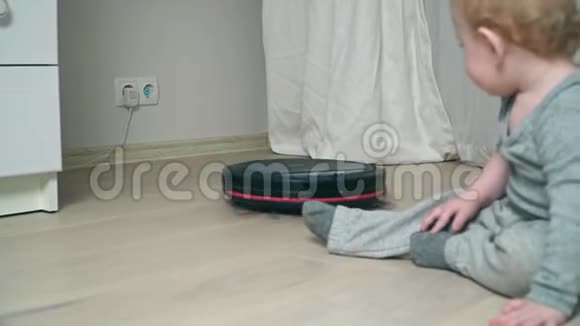 机器人吸尘器在地板上男婴在木地板上视频的预览图