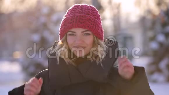 冬天戴粉色针织帽子的女人的肖像慢镜头视频的预览图