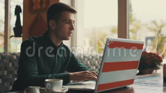 远处看着一个年轻的商人坐在咖啡馆的桌子旁看着过路人成功人士日常生活视频的预览图