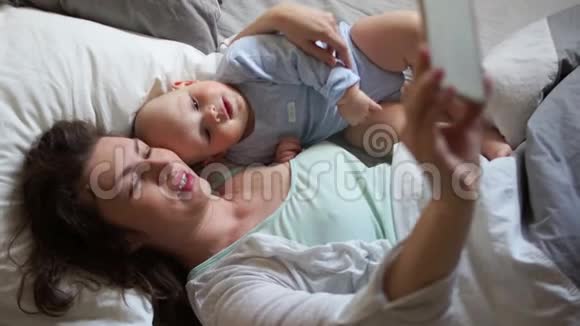 妈妈和宝宝躺在床上自拍母亲节家人早上好智能手机和宝宝视频的预览图