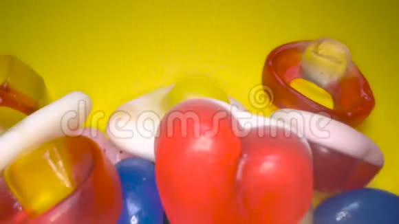 滑过一堆美味缤纷的咀嚼糖果背景黄色背景的彩色糖果视频的预览图