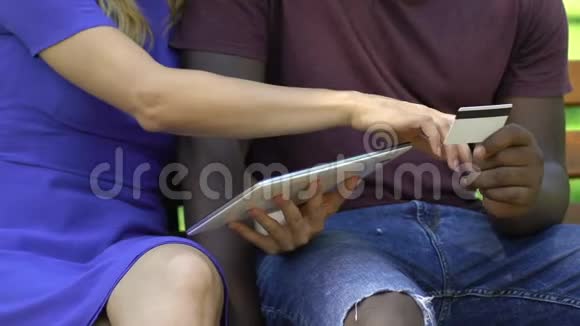 年轻的混血夫妇坐在长凳上一起在网上购物休息视频的预览图